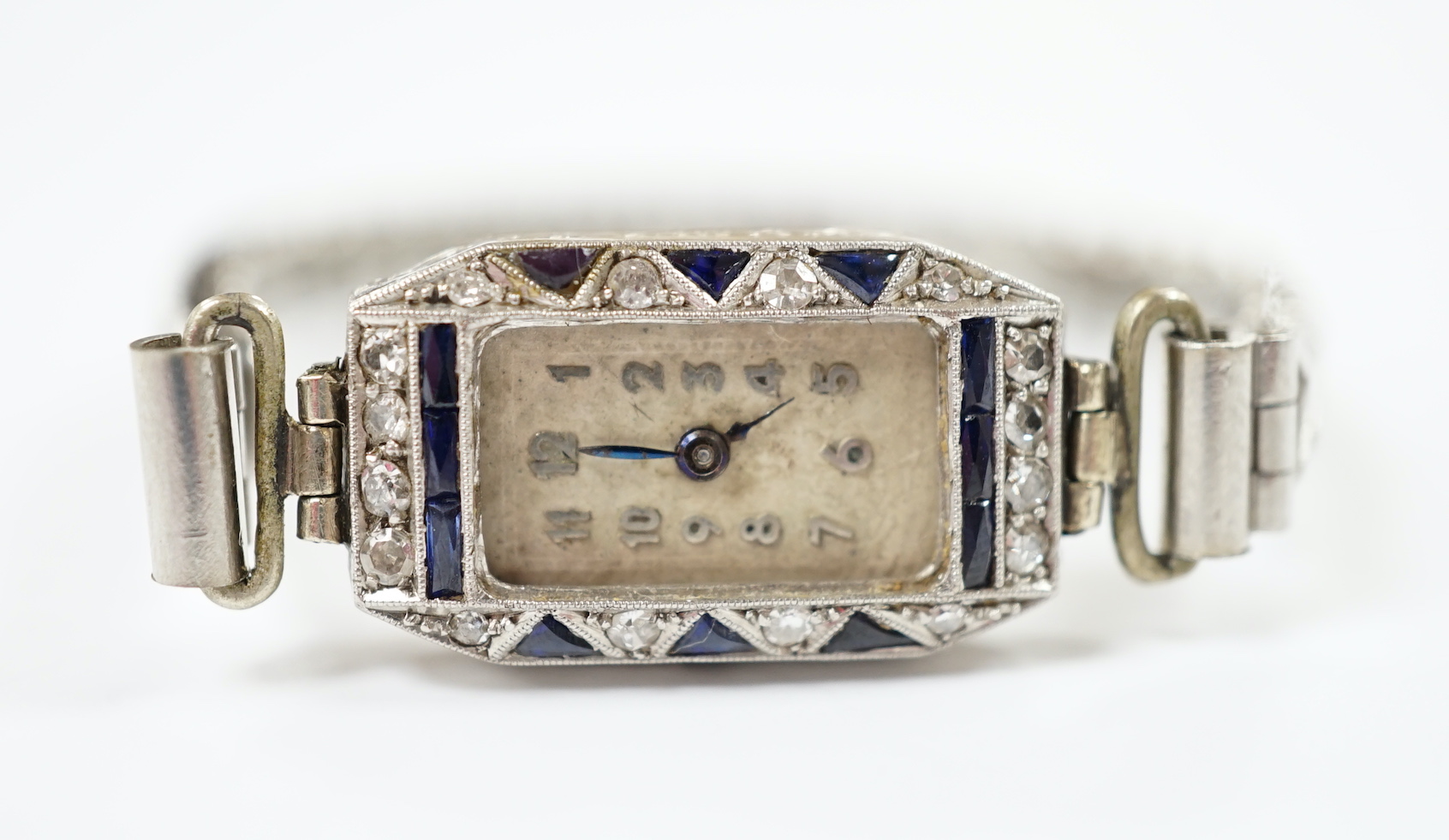 A lady's 1930's white metal (stamped platina), diamond and sapphire set manual wind cocktail watch (no glass or winding crown), on a stainless steel expanding bracelet.